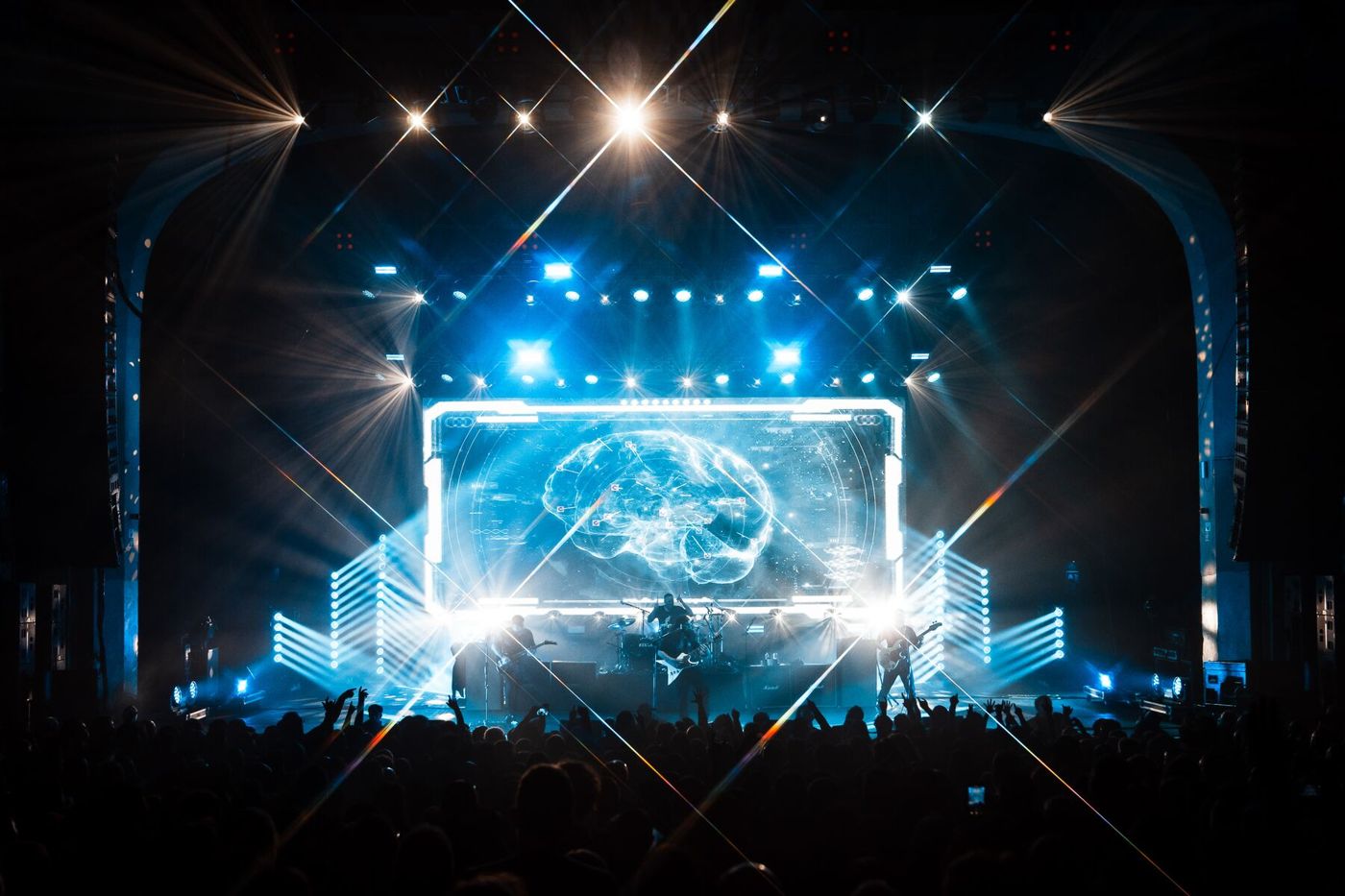 Coheed and Cambria in a theatre, a framed video screen centre stage with blue light and starburst beams