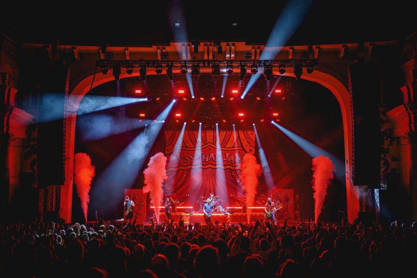 Less Than Jake in a theatre bathed in red, with CO2 jets firing and white beams across the stage