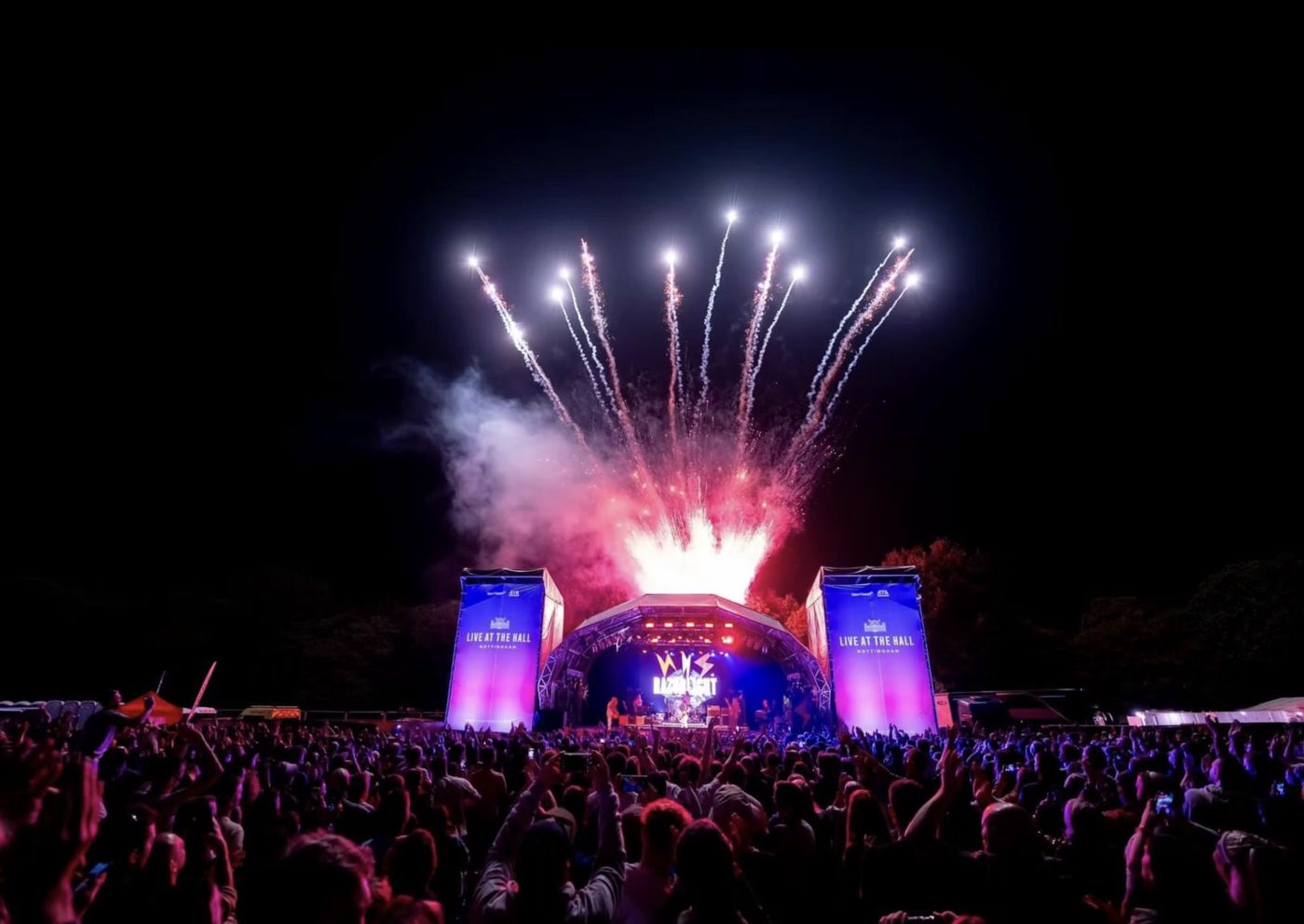 Razorlight headlining an outdoor stage as fireworks burst overhead and the crowd raises their hands